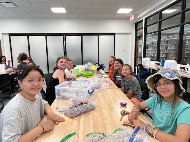 Group of teens at a table smiling as they craft