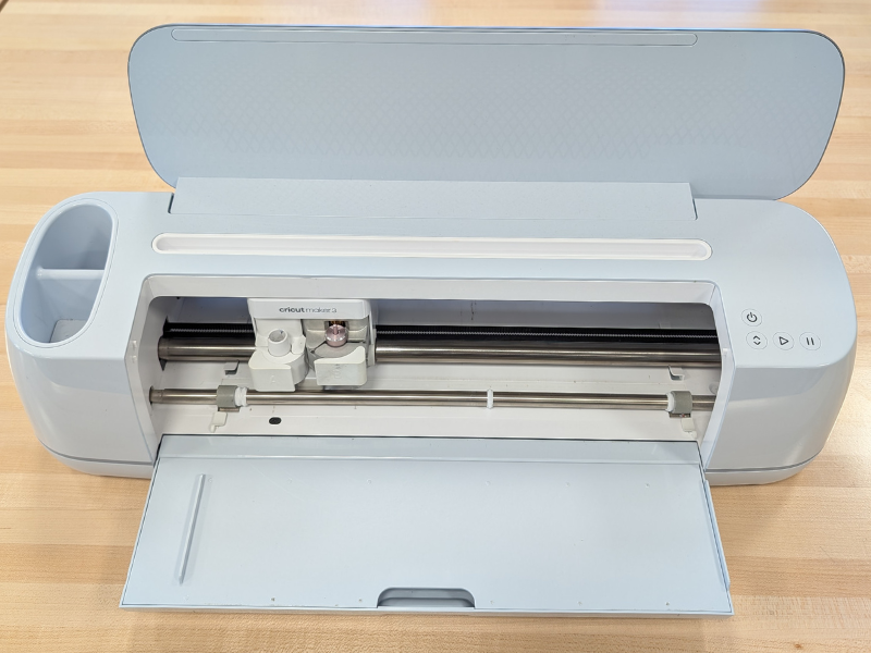 A Cricut Maker 3 machine with the top and front compartments opened up.