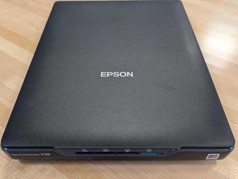 Black Epson Perfection V39 machine sitting on a wooden table