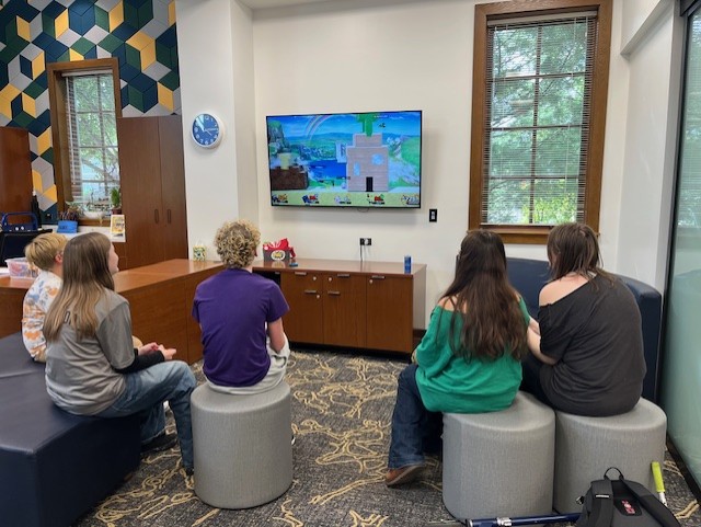 Group of five teens playing a switch game inside the library