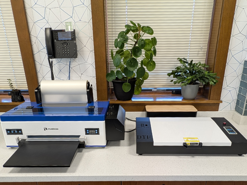 Punehod DTF Printer on a white counter with plants in the back and a wooden window sill