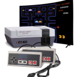 First edition Nintendo console with two controllers. Desktop monitor in the back with Pac Man on the screen.