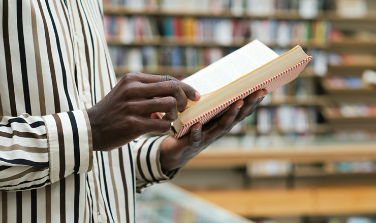 man holding an open book in the library