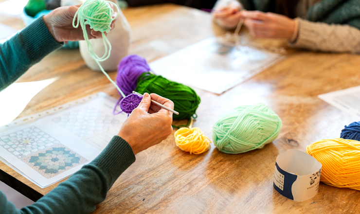 Two people sitting at a table and unspooling yarn to start crochet projects