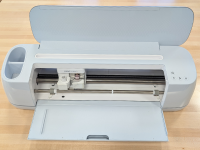 A Cricut Maker 3 machine with the top and front compartments opened up.