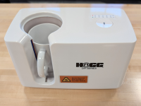 White Hogg Mug Press machine with an orange warning label sitting on a wooden table.