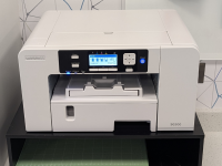 A white Sawgrass SG500 Sublimation machine on a white counter with a white and grey backsplash on the wall behind the machine.